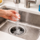 Running water and ice cubes cleaning a garbage disposal in a kitchen sink to remove food buildup
