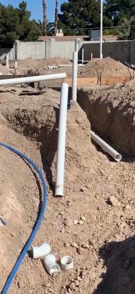Underground water line repair service in Las Vegas with exposed supply pipes in trench