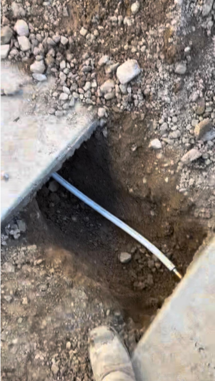 Main water line repair in Las Vegas NV with underground pipe exposed in trench beside concrete slab