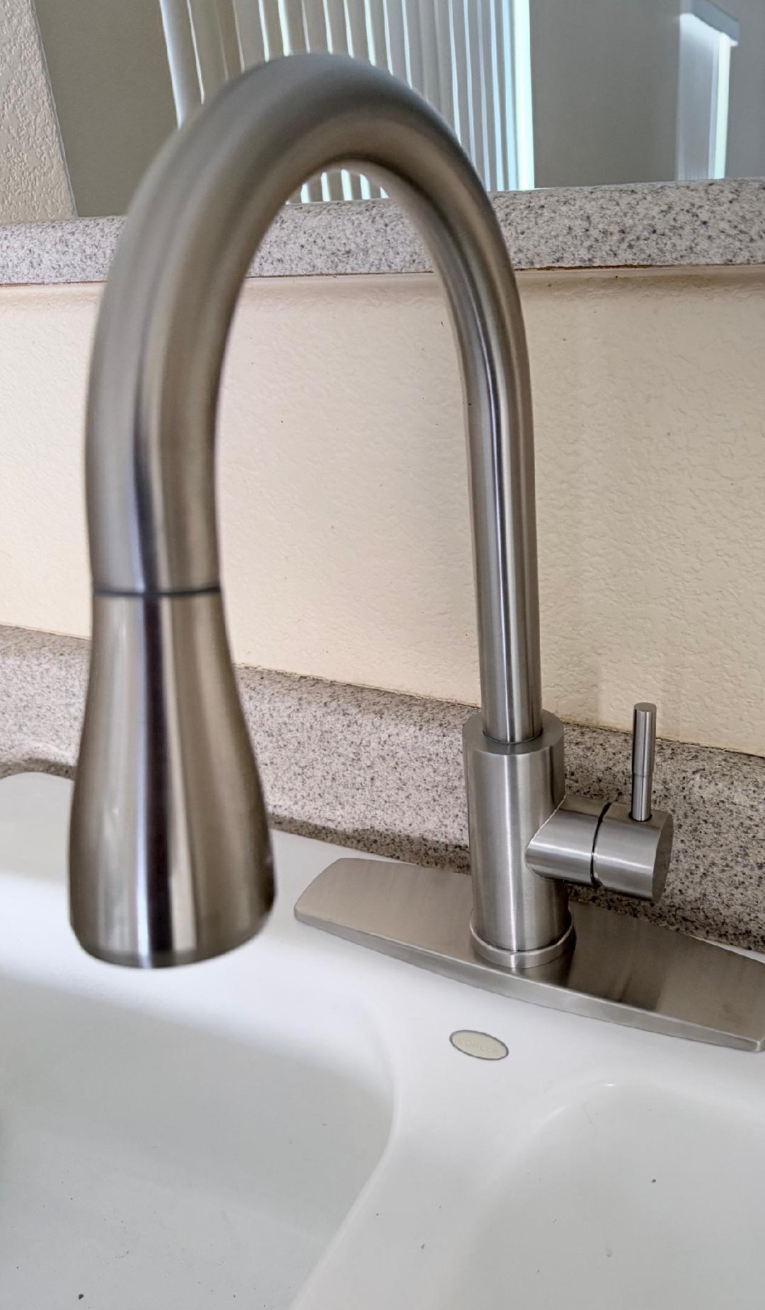 Brushed nickel single handle pull-down kitchen faucet installed on white farmhouse sink by Plumbing Repair Experts in Las Vegas, NV