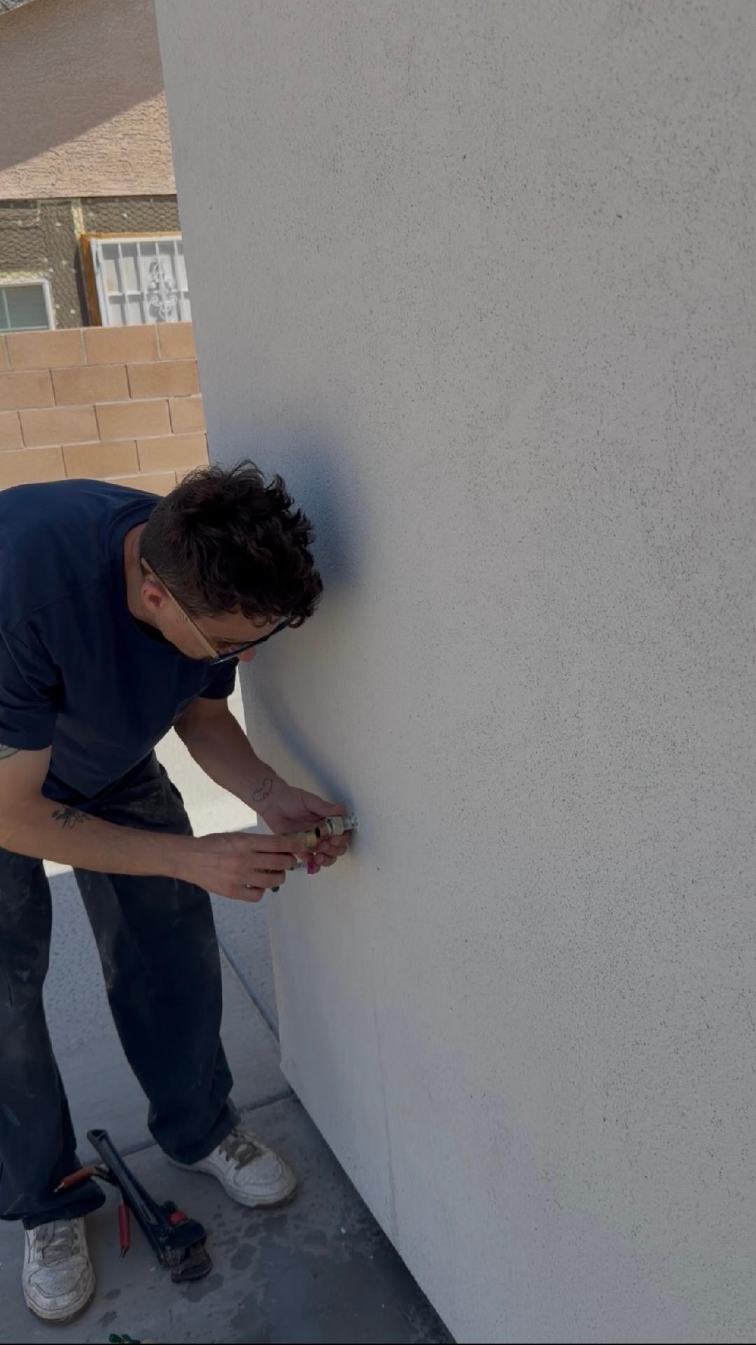 Plumbing Repair Experts technician repairing exterior hose bib on stucco wall at Las Vegas NV residential property
